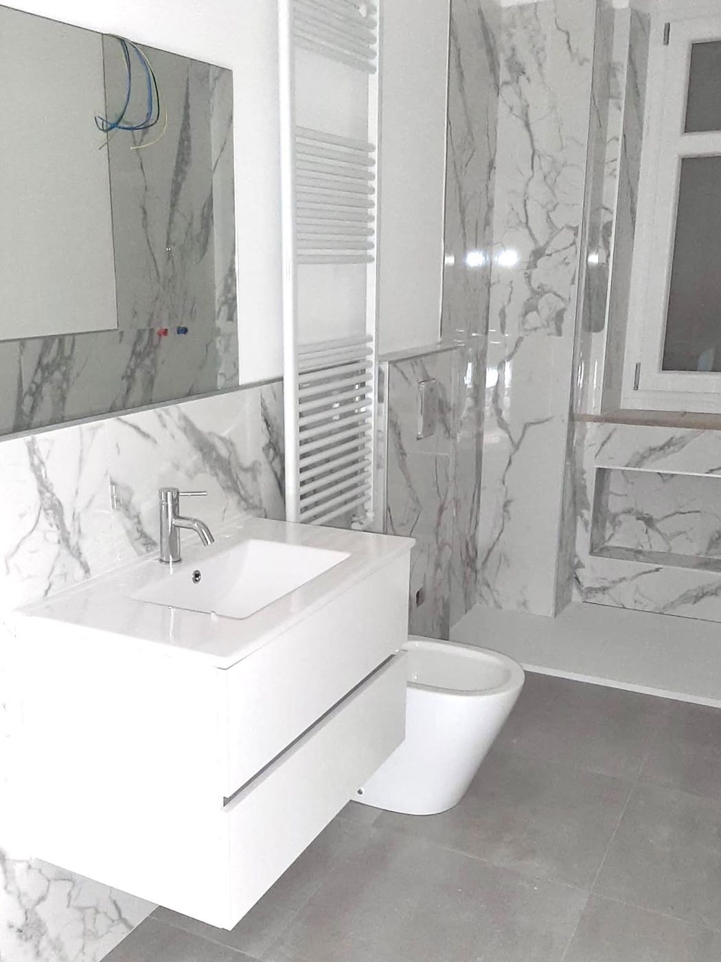 Bagno con rivestimento effetto marmo bianco e mobile sospeso